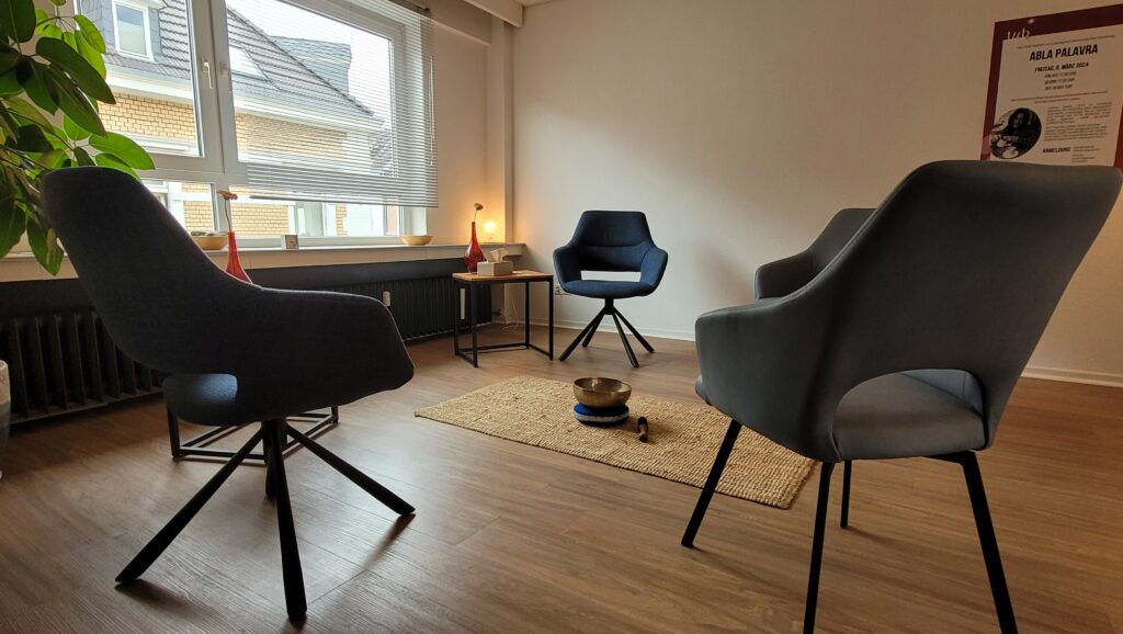 Vier Stühle stehen im Kreis im großen Therapieraum. In der Mitte steht eine große Klangschlage auf dem Boden.
